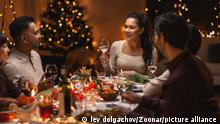 holidays, party and celebration concept - multiethnic group of happy friends having christmas dinner at home and drinking wine || Modellfreigabe vorhanden
