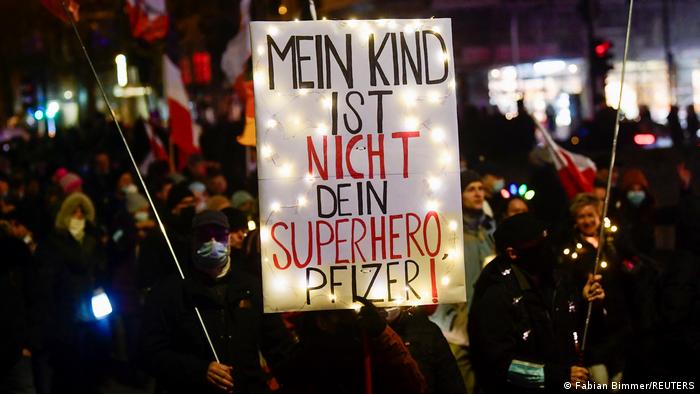 A protester in Hamburg holds a placard with the words: 'My child is not your superhero, Pfizer!'
