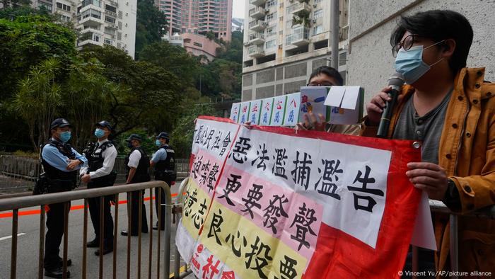 Protesters hold up a banner close to fence guarded by police