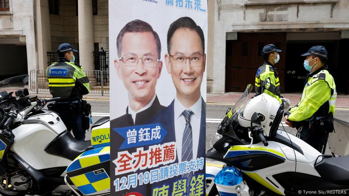 Police officers stand next to police motorcycles with an electoral poster in the middle