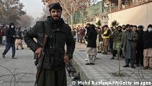 A Taliban fighter stands guard at a checkpoint as people queue to enter the passport office in Kabul on December 19, 2021, after Afghanistan's Taliban authorities said they will resume issuing passports. (Photo by Mohd RASFAN / AFP) (Photo by MOHD RASFAN/AFP via Getty Images)