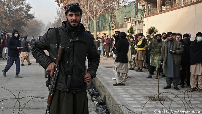 Боєць Талібану стоїть на блокпосту біля черги у паспортний стіл у Кабулі, грудень 2021 року