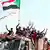 Sudanese youths raise their national flag at protests