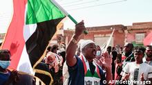 A Sudanese demonstrator waves a national flag as he shouts slogans during a rally against the military chief who launched an October 25 coup followed by a bloody crackdown, in the northern part of the capital Khartoum, on December 19, 2021. - Thousands of Sudanese protesters rallied today to mark three years since the start of mass demonstrations that led to the ouster of strongman Omar al-Bashir and as fears mount for the democratic transition. (Photo by AFP) (Photo by -/AFP via Getty Images)