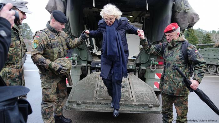 Christine Lambrecht springt von der Ladefläche eines Kleinlasters und lässt sich dabei von zwei Soldaten helfen.