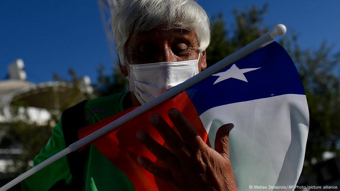 A older supporter of Gabriel Boric kisses the Chilean flag