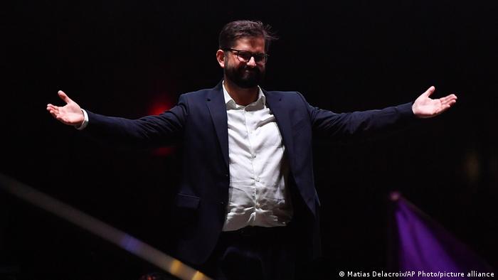 Gabriel Boric stands with his arms outstretched