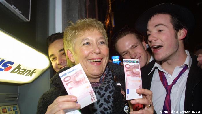 Жительница нидерландского Маастрихта радуется 1 января 2002 первым взятым из банкомата купюрам евро 