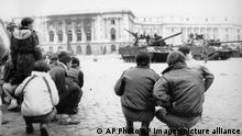 Civilians stay low and watch the tanks that are parked outside the Royal Palace in Bucharest on December 24, 1989, as the fighting between regular army and SECURIATE troops loyal to ousted Romanian President Ceausescu continues. (AP Photo)