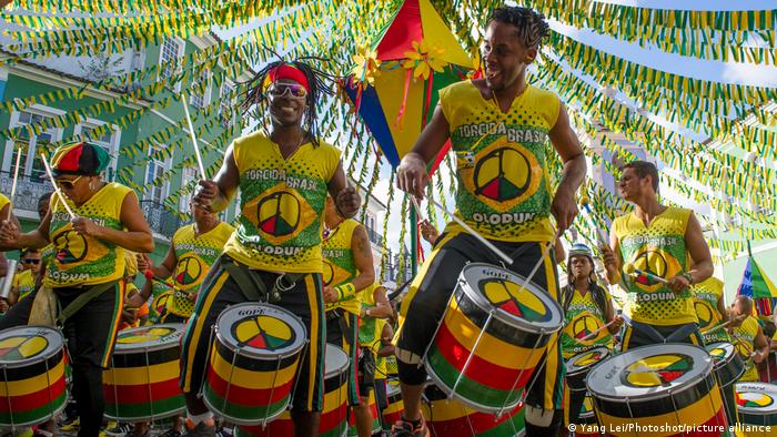 Mitglieder der Torcida Brasil Olodum spielen, farbenfroh angezogen, auf Trommeln