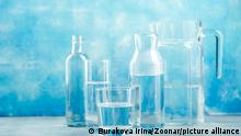 Group of empty glass jars and bottles with clear water on blue background
