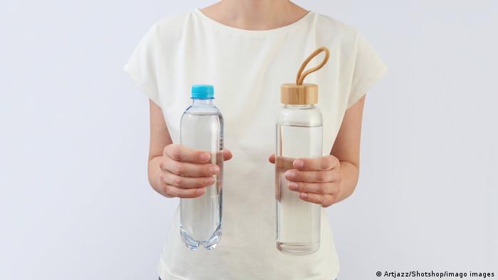 Eine Frau hält zwei Glasflaschen für Trinkwasser in ihren Händen