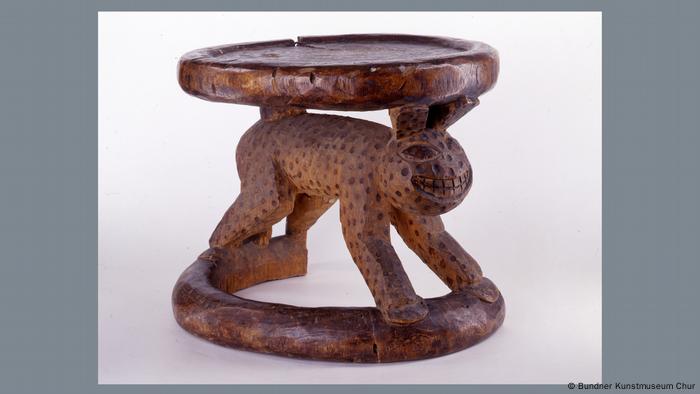 A wooden stool with a human-leopard like figure carved as its legs