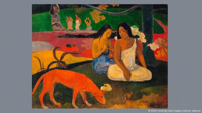 A painting by Gaugin in which two indigenous women sit with crossed legs on the ground in a forest while a dog is in front of them