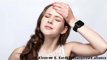 Portrait of beautiful woman with freckles and white dress and smart watch with headache pain on silver gray background. healthcare and medicine concept. || Modellfreigabe vorhanden