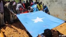Family members hold the naitonal flag as they bury the body of Abdiaziz Mohamud Guled, the director of government-owned Radio Mogadishu, in Mogadishu, Somalia, on November 21, 2021. - A prominent Somali journalist who was a staunch critic of jihadist group Al-Shabaab was killed by a suicide bomber as he left a restaurant in the capital Mogadishu on November 20, officials and colleagues said. (Photo by AFP)