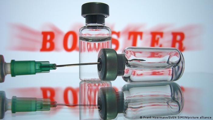 Two vials and a needle in front of the word booster