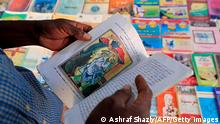 Bookseller Yaqoub Mohamed Yaqoub, 45, shows a picture illustrating the Cubism art movement in a book, by his roadside stall where he has been working for 15 years, in the Sudanese capital Khartoum, on January 14, 2021. - As Sudan's transitional government shifts the nation from the Islamist rule of ousted strongman Omar al-Bashir, a new school book has sparked controversy for reproducing Michelangelo's iconic Creation of Adam. (Photo by ASHRAF SHAZLY / AFP) (Photo by ASHRAF SHAZLY/AFP via Getty Images)
