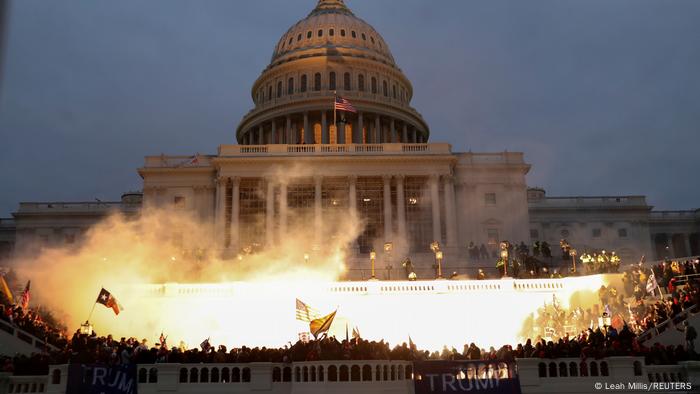 A large crowd, fire and flags outside the US Capitol.