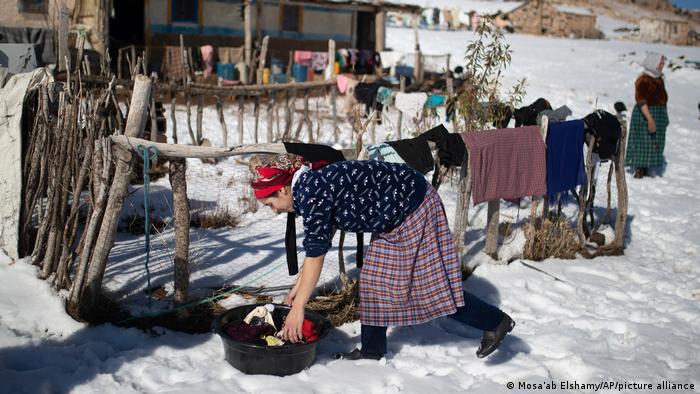 Eine Frau kümmert sich in verschneiter Landschaft um die Wäsche im Bergdorf Timahdite in Marokko, (AP Photo/Mosa'ab Elshamy)