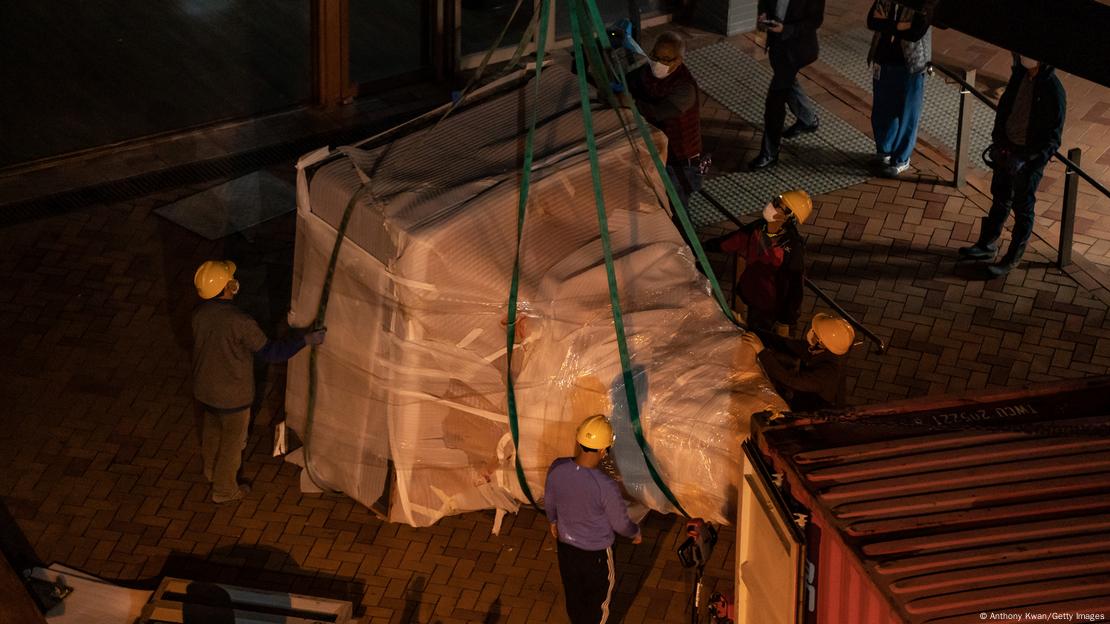 Foto mostra trabalhadores transportando parte de escultura.