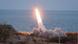Eine Rakete wird an einem Küstenstreifen direkt am Meer abgefeuert Eine Rakete wird an einem Küstenstreifen direkt am Meer abgefeuert