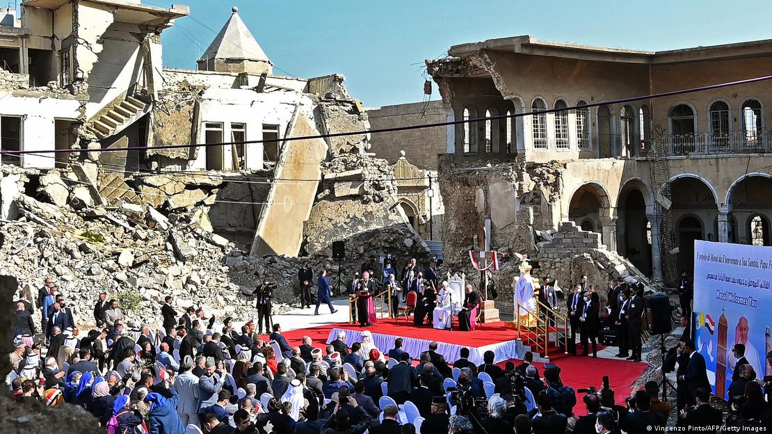 Foto de 2021 mostra o papa Francisco falando para o público de cima de um palanque montado numa praça em Mossul que estava cercada por ruínas