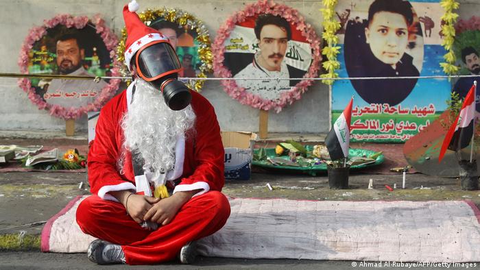 An Iraqi demonstrator wearing a Santa Claus costume and a gas mask sits on a blanket in the capital Baghdad's Tahrir Square, amid ongoing anti-government protests, on December 6, 2019. 