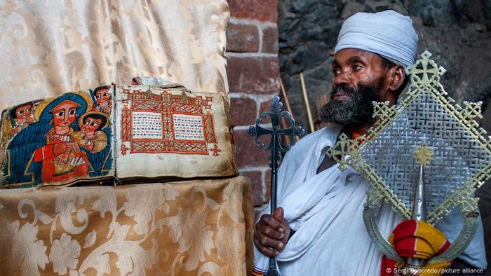 An orthodox priest stands with a cross