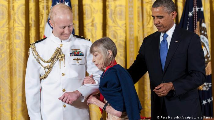 US author Joan Didion (centre) is escorted from the stage after being presented a 2012 National Humanities Medal by US President Barack Obama (right