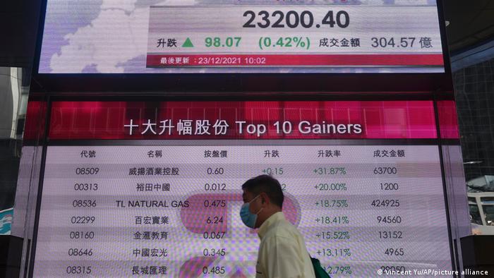 A man walks past a bank's electronic board showing the Hong Kong share index at Hong Kong Stock Exchange Thursday, Dec. 23, 2021. 