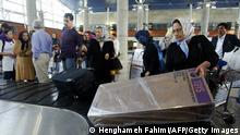 TEHRAN, IRAN: Iranian passengers take their luggage as they arrive from Dubai to Tehran's newly re-opened Imam Khomeini airport 30 April 2005. The Iranian capital's new showpiece airport finally reopened today a year after being shut down by the armed forces, but was immediately hit by fresh controversy amid warnings its runway may not yet be safe. AFP PHOTO/HENGHAMEH FAHIMI (Photo credit should read HENGHAMEH FAHIMI/AFP via Getty Images)