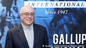Kancho Stoychev stands in front of a sign for Gallup International, wearing glasses