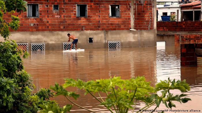 A man tries to recover furniture through the window of his house due to flooding caused by intense rains in the city of Itapetinga, in the southern region of the state of Bahia