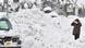 Heavy snow at a street in Tottori City covers a car, as a person is dwarfed by a snowbank Heavy snow at a street in Tottori City covers a car, as a person is dwarfed by a snowbank