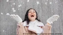 Optimistic young woman smiling while having fun on street on sunny winter day || Modellfreigabe vorhanden