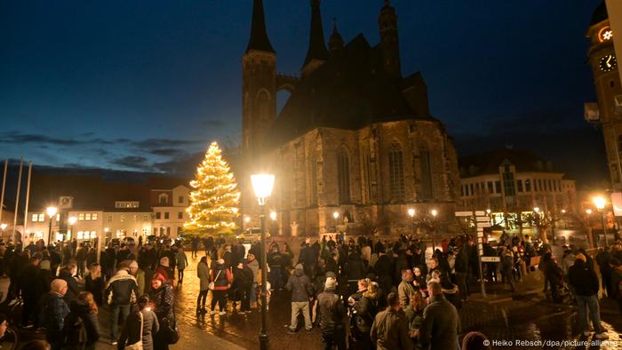 Des manifestants sur la place du marché de Köthen, un arbre de Noël illuminé est visible