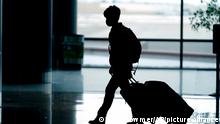 A silhouette image of a person with wheeled luggage