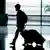 A silhouette image of a person with wheeled luggage