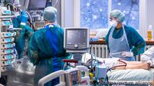 ARCHIV - 30.11.2021, Mecklenburg-Vorpommern, Rostock: Ärzte und Pflegekräfte betreuen einen Patienten bei einer Lungenspiegelung in einem der Behandlungszimmer auf der Intensivstation in der Universitätsmedizin Rostock. Die vierte Corona-Welle scheint zumindest etwas abzuklingen. Doch Omikron könnte die Entwicklung schon bald wieder umkehren. (zu dpa: Corona-Lage entspannt sich offenbar etwas - aber Omikron lauert schon) Foto: Jens Büttner/dpa-Zentralbild/dpa +++ dpa-Bildfunk +++