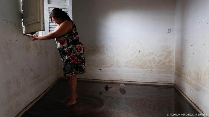 Rosimary Goncalves, de 49 años, mira por la ventana de su casa inundada.