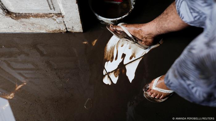 Un hombre barre el barro con los pies.
