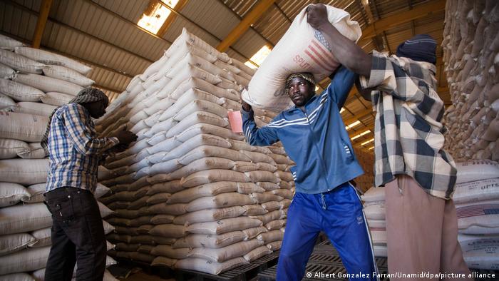 A handout photo made available on 12 February 2014 by the United Nations-African Union Mission in Darfur (UNAMID) shows World Food Programme (WFP) staff members loading bags of split yellow peas into a truck in a WFP warehouse based in El Fasher, North Darfur