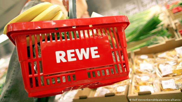 A woman carries a REWE vbasket at a store in Cologne