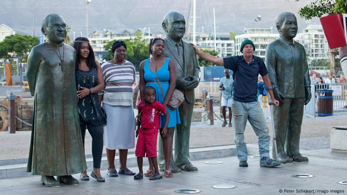 Tourists stand in front of statues of Desmond Tutu, Frederik Willem de Klerk and Nelson Mandela