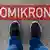 A pair of feet standing in front of a text on a pavement reading "Omikron"