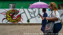 Two women walk past a COVID-19 graffiti in Soweto's Orlando West township near Johannesburg, South Africa, Thursday Nov. 19, 2020. Africa has surpassed 2 million confirmed coronavirus cases as the continent's top public health official warns that “we are inevitably edging toward a second wave” of infections. The 54-nation continent of 1.3 billion people is being warned against “prevention fatigue” as countries loosen pandemic restrictions to ease their economies’ suffering and more people travel. (AP Photo/Jerome Delay)