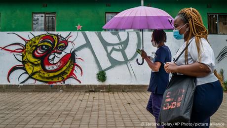 Two women walk past a COVID-19 graffiti in Soweto's Orlando West township near Johannesburg, South Africa.