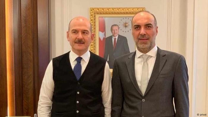 Two men in front of a portrait of Turkish President Precep Tayyip Erdogan