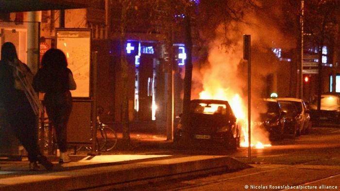 People observe a car that has been set on fire in Strasbourg, France